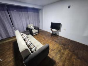 a living room with a couch and a tv at Departamento esmeralda in Chota