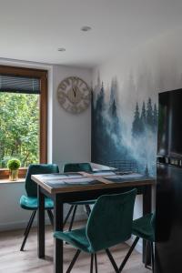 a dining room with a table and chairs and a clock at Domek Pod Czereśnią in Szczawnica
