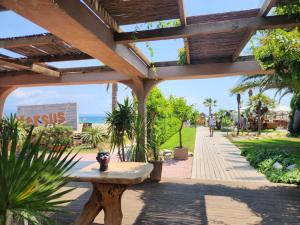a wooden pergola with a bench in a park at Garden maisonnette 2-bedrooms sleeps 6 adults 200m from sandy beach in Asprovalta