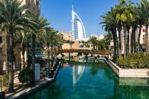 a river in a city with palm trees and a bridge at Rahaal 1 BDR, Madinat Jumeirah in Dubai