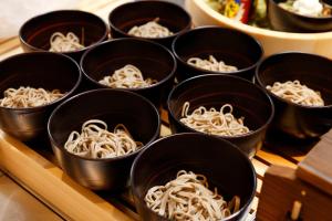 a bunch of black cups filled with noodles at Dormy Inn Nagano in Nagano