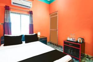 a bedroom with orange walls and a bed and a window at Hotel O by OYO ALO Hotel in Phulbāri