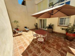 a patio with a table and chairs and an umbrella at Appartement duplex avec cour extérieure Avignon centre in Avignon