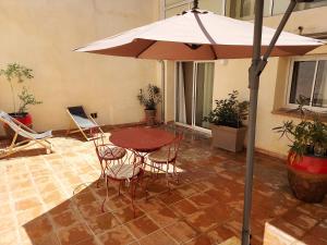 a table and chairs and an umbrella in a courtyard at Appartement duplex avec cour extérieure Avignon centre in Avignon +3 photos