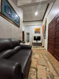 a living room with a leather couch and a television at Sha Homestay in Marang