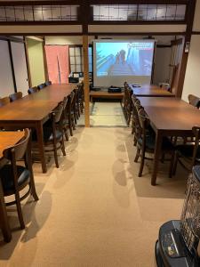 a room with tables and chairs and a large screen at Hot Spring Inn Hyoutan in Kusatsu