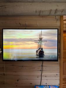 a tv hanging on a wall with a ship in the water at Grasbakken hytteutleie in Nesseby