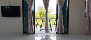 a room with a television and a balcony with a table at MyMama Homestay in Pasir Mas