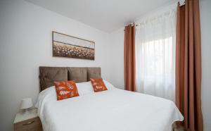 a bedroom with a white bed and a window at Apartments Sanja in Zaton