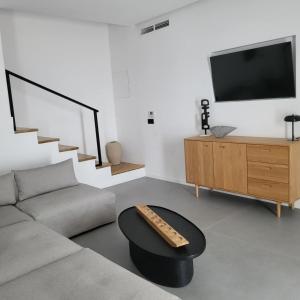 a living room with a couch and a tv at Oro suites view in Mýkonos City