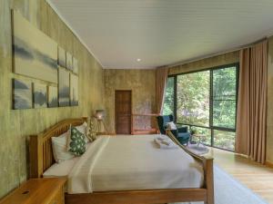 a bedroom with a large bed and a large window at The Stream House in Ban Pok Nai
