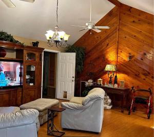 a living room with white furniture and wooden walls at West Tawakoni Lake House in West Tawakoni