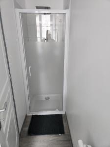 a walk in shower with a black rug in a bathroom at Appartement 103 in Avallon