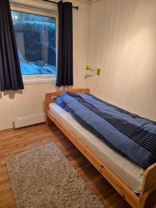 a bedroom with a bed with a window and a rug at Roligheten hytte in Farsund +7 photos