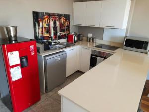a kitchen with a red refrigerator and white cabinets at Apartment near V&A Waterfront & Convention Centre in Cape Town