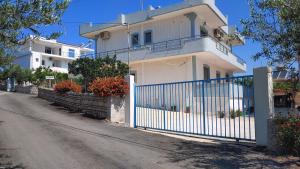 a white house with a blue fence next to a street at Villa Zeka Ksamil in Ksamil