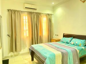 a bedroom with a bed and a window with curtains at Coral Place in Abeokuta