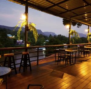 a bar with tables and chairs on a deck at Rimwang The River Life in Sai Yok