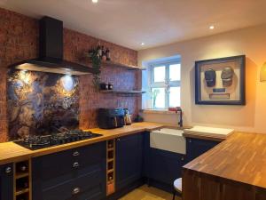 a kitchen with blue cabinets and a brick wall at Executive 1bd 1st floor flat in Caerleon