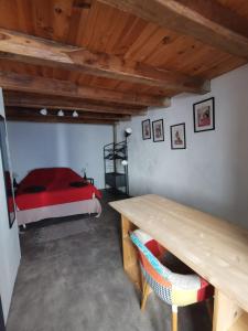 Un dormitorio con una cama roja y una mesa de madera. en Duplex à inaugurer, en Florac