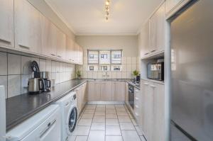 a kitchen with wooden cabinets and a washer and dryer at 23 Madriko - Visit Langebaan in Langebaan