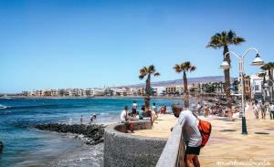 a man looking over a wall near the ocean at Casa Klemann with private sun terrace in Cruce de Arinaga