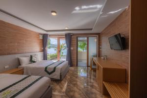 a hotel room with two beds and a television at Phu Ninh Lake Resort & Spa in Tam Ky