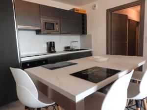 a kitchen with a table and white chairs at Splendide T3 neuf au bord de la plage in Propriano