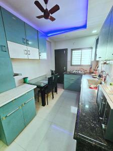 a kitchen with blue cabinets and a ceiling fan at Beautiful Appartment in Indore