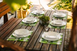 a wooden table with white plates and glasses on it at Homestead Lukec Studio Apartments - Archery, BBQ, Escape Room, Kayaking in Kostel