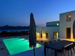 a villa with a swimming pool and a table with chairs at Antiparos Gems in Agios Georgios