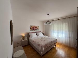a white bedroom with a bed and a window at Apartment Carmen in Trogir
