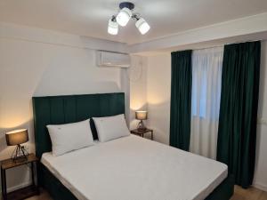 a bedroom with a large bed with a green headboard at Vila Andora in Eforie Nord