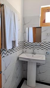 un bagno bianco con lavandino e specchio di Adventure Sarai Hotel Skardu a Skardu