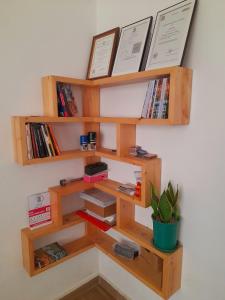 ein hölzernes Bücherregal mit Büchern und einer Topfpflanze in der Unterkunft Beskydy Holiday Rentals in Mbeya