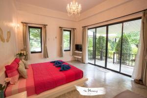 a bedroom with a red bed and a large window at The Harmony Resort in Suan Phung