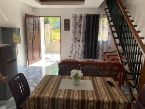 a dining room with a table and chairs and a staircase at 3Vhin Transient House in Sampong