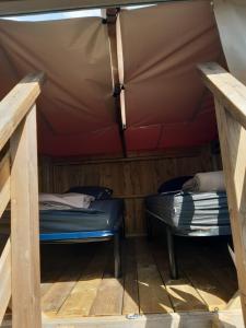 La VarenneにあるCamping Onlycamp Les Grenettesのテント内のベッド2台が備わる部屋