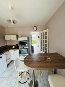 a kitchen with a wooden table and white chairs at Maison située aux confins de la Vallée du Loir in Le Lude