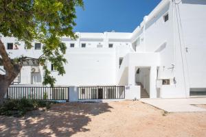 a white building with a gate and a tree at Pado Living in Faliraki +44 photos
