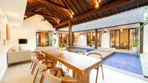 comedor con mesa, sillas y piscina en Apple Villa & Suite Seminyak, en Seminyak