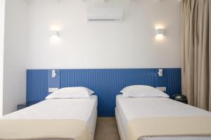 two beds in a hotel room with blue walls at FarOut - BeachResort & Camping in Mylopotas