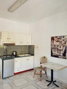 a kitchen with white cabinets and a table at LAINAS apartments in Nea Skioni