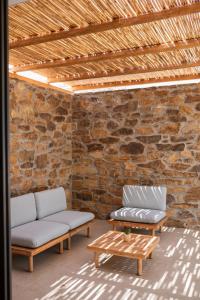 two couches and a coffee table in front of a brick wall at FarOut - BeachResort & Camping in Mylopotas