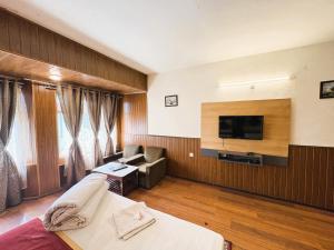 a hotel room with a bed and a television at Near Chauk Bazaar Marvel International & Restaurant HD Lama Rd in Darjeeling