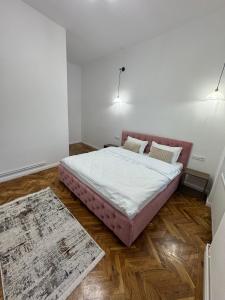 a bedroom with a large bed with white sheets and wooden floors at FLH - Central Oasis in Sibiu