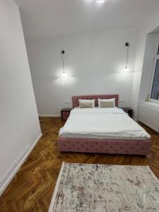 a bedroom with a bed with white sheets and a rug at FLH - Central Oasis in Sibiu