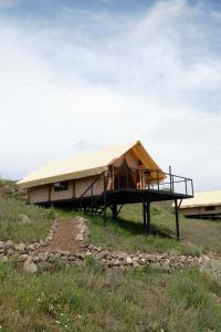 un grande edificio con un tetto di tela in un campo di Yagoda Moya a Khot