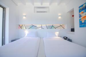 two beds in a room with white walls at FarOut - BeachResort & Camping in Mylopotas