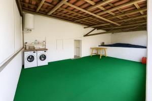a room with a green floor and a washing machine at Freedom Surf House in Serra de El-Rei +17 photos